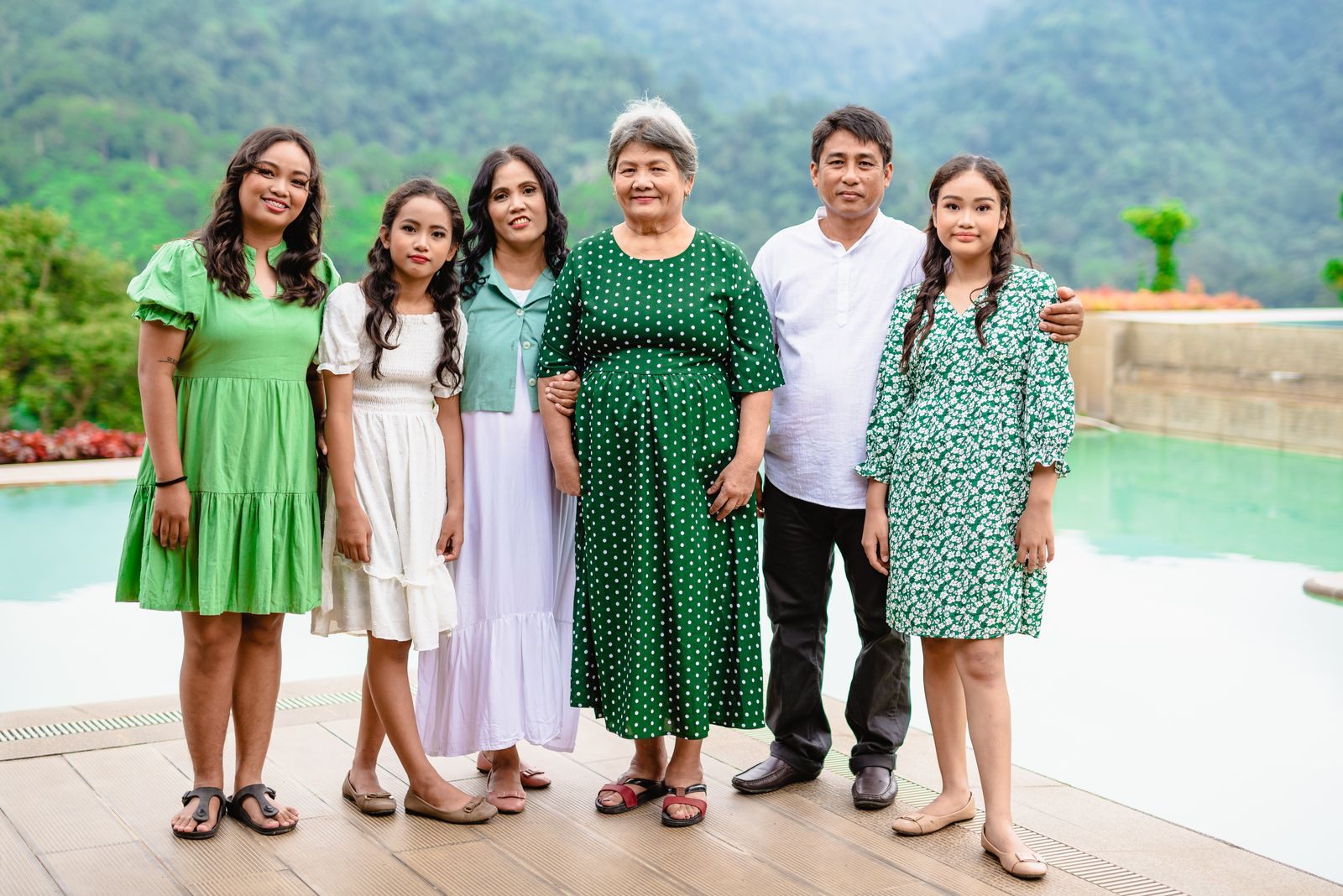Three generations of a family posing together beside a resort pool, the kind of party that asks how to organize a group cruise